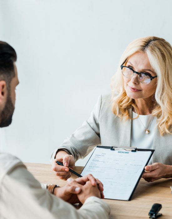 selective-focus-of-recruiter-in-glasses-holding-pen-near-clipboard-and-looking-at-bearded-man.jpg
